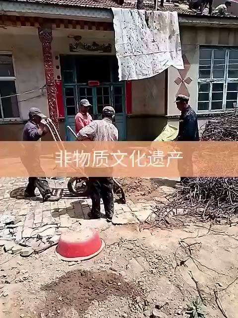 Three workers clear debris outside a rural building with a Chinese banner reading “intangible cultural heritage.”