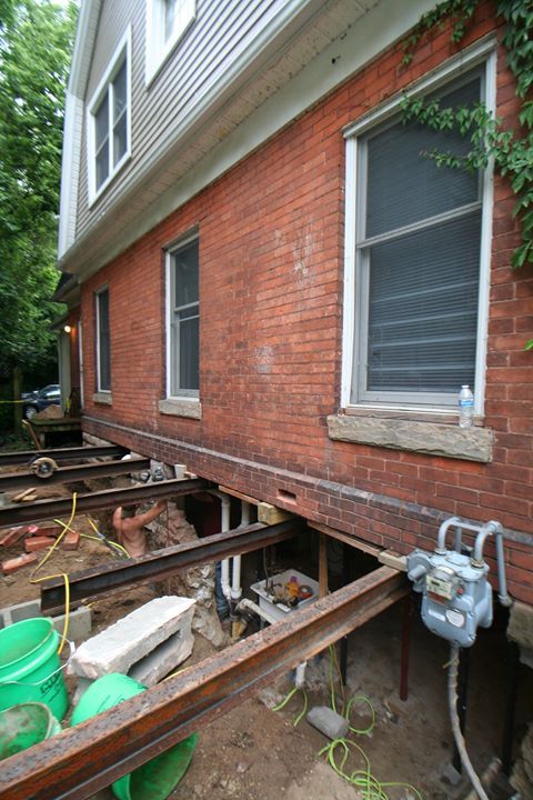 Brick house exterior with exposed foundation beams and crawlspace under construction