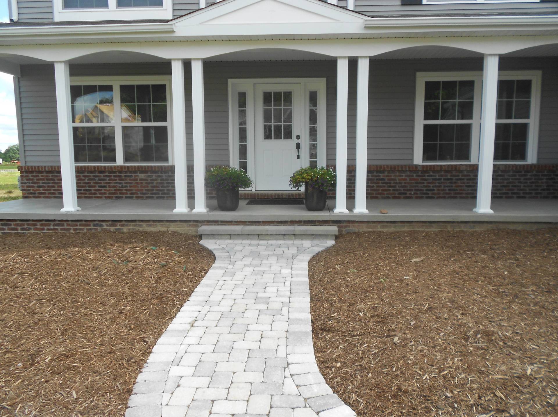 Front porch of a house with white columns and a stone walkway leading to the entrance.