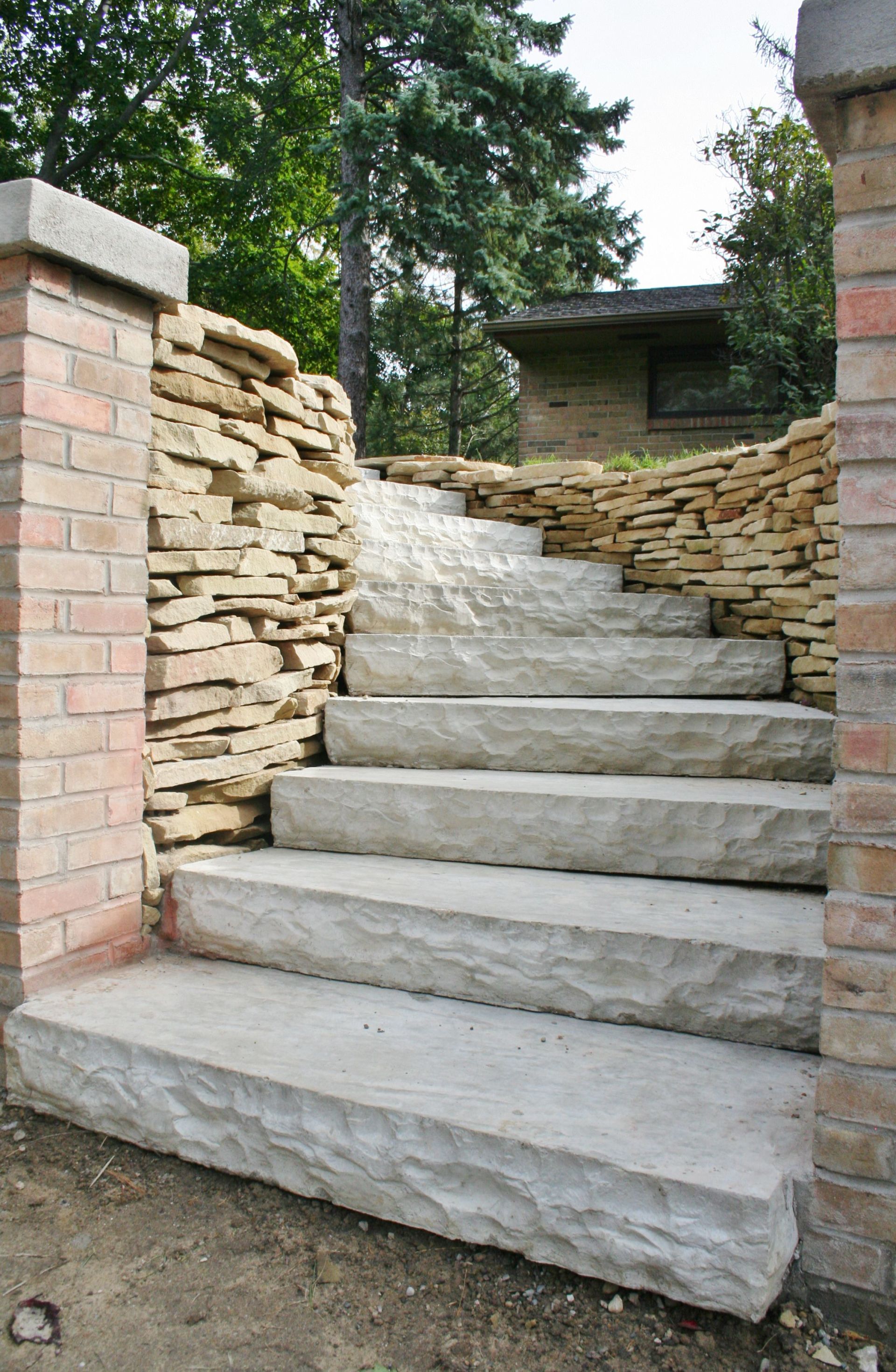 Stone steps leading up between brick walls and stacked stone in a garden setting