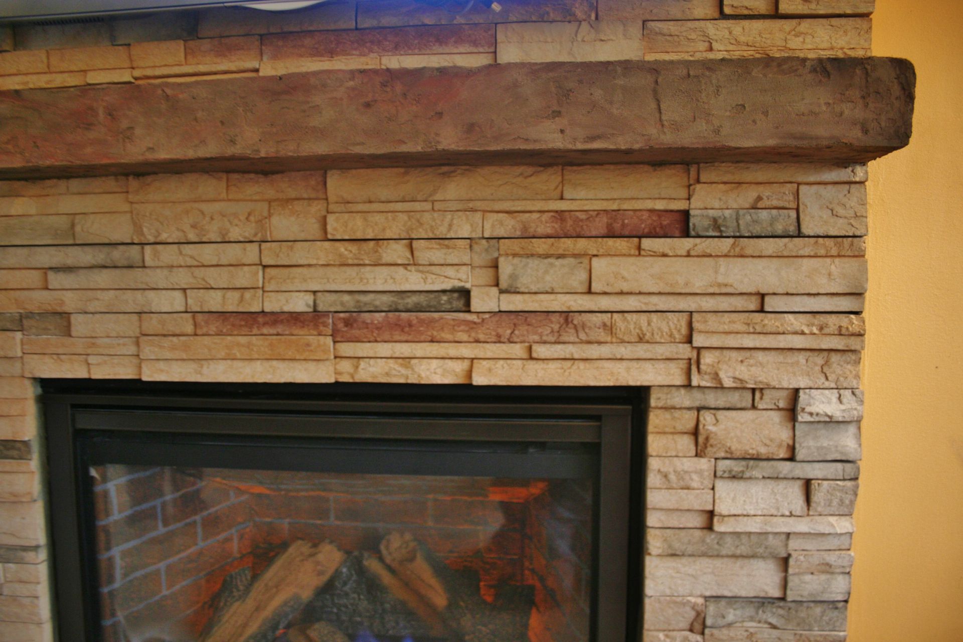 Stone fireplace mantel with a black glass firebox insert