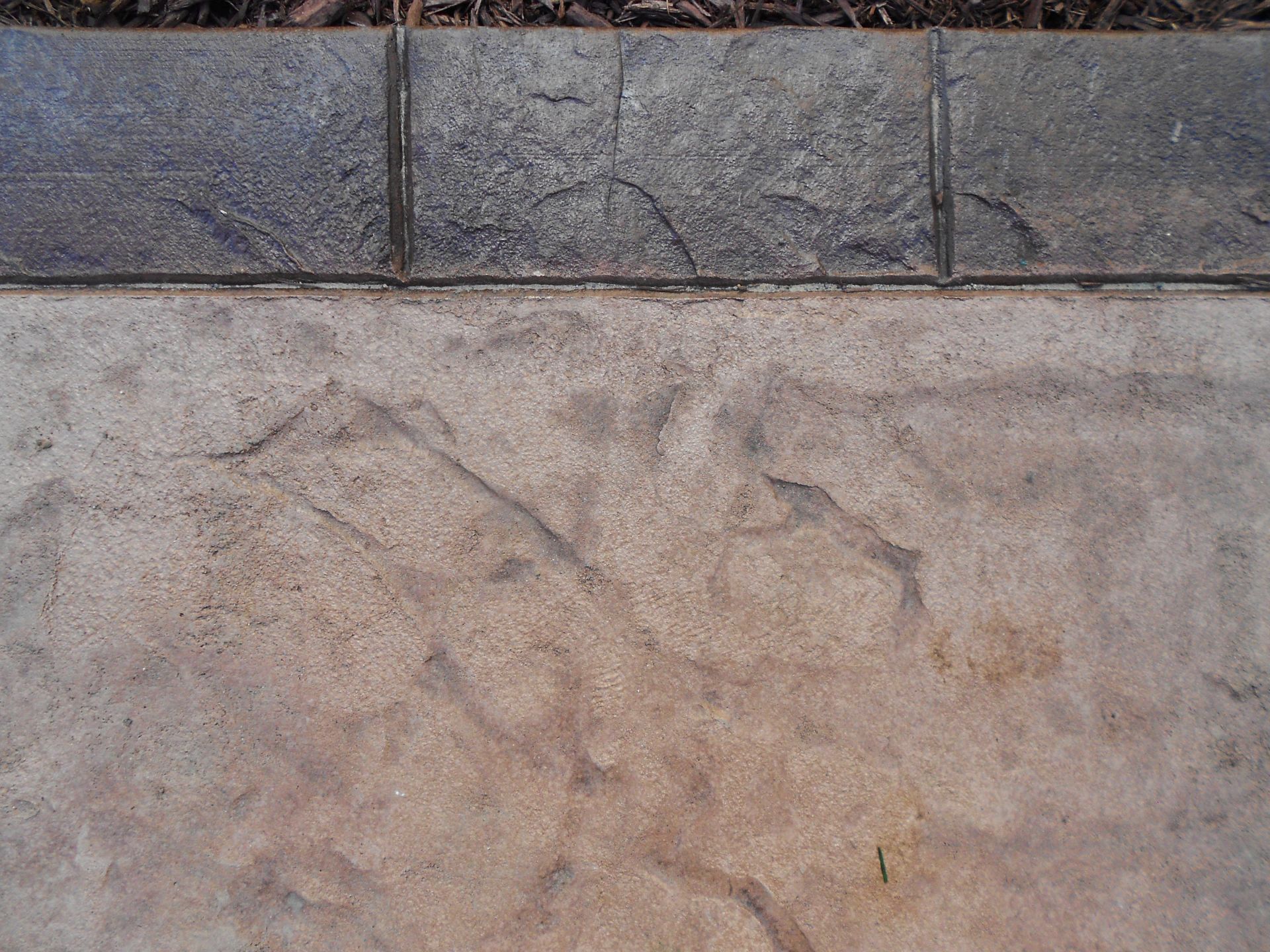 Stone paving with a dark curb along the top edge and a light, weathered surface below