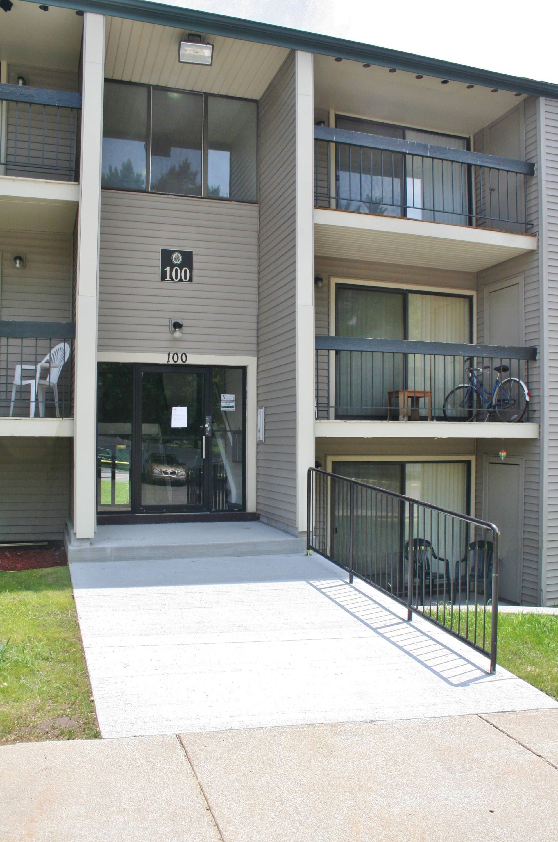 Apartment building entrance with concrete ramp, stairs, and balconies.