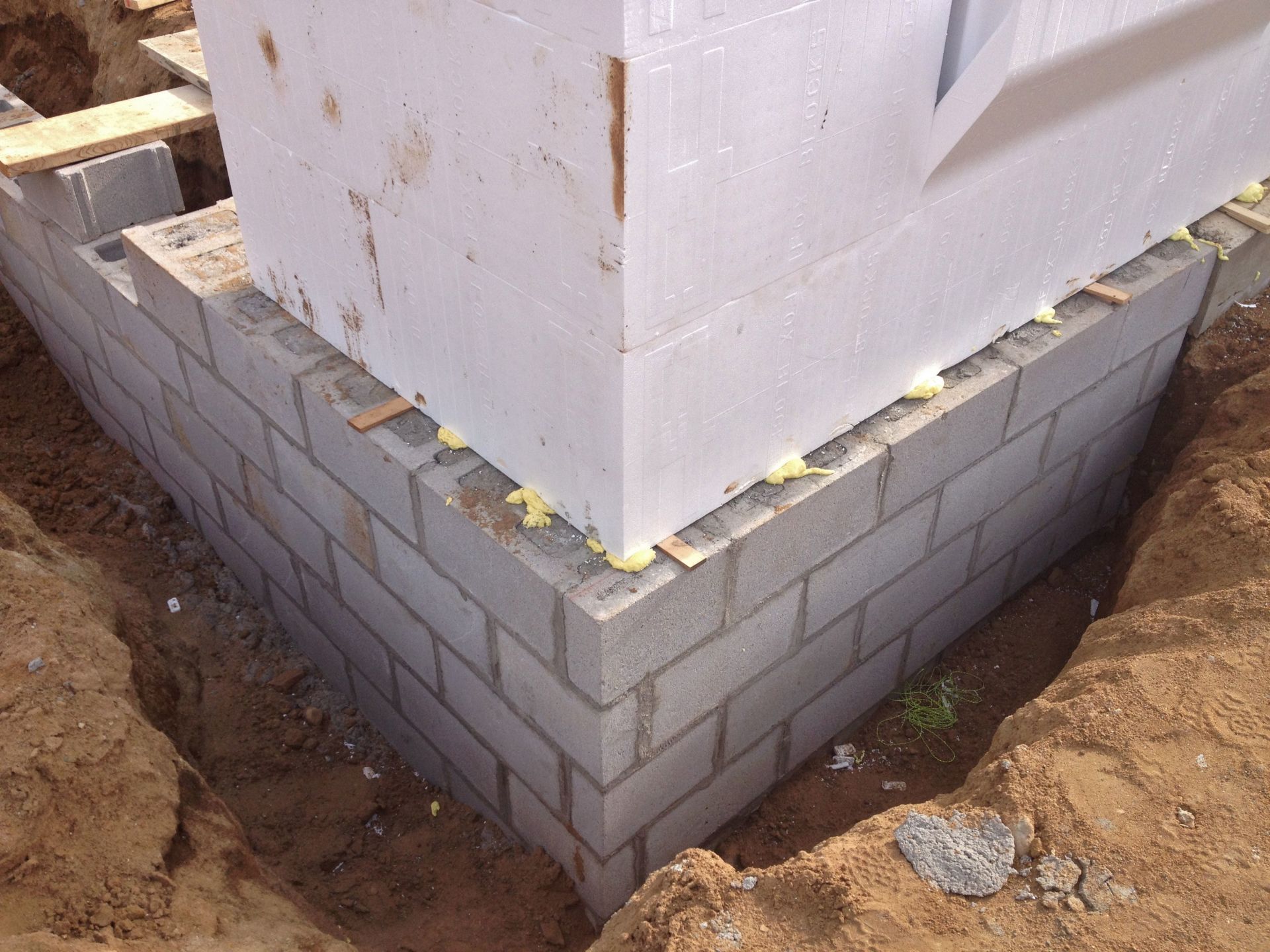 White building corner on gray block foundation in a dirt excavation site