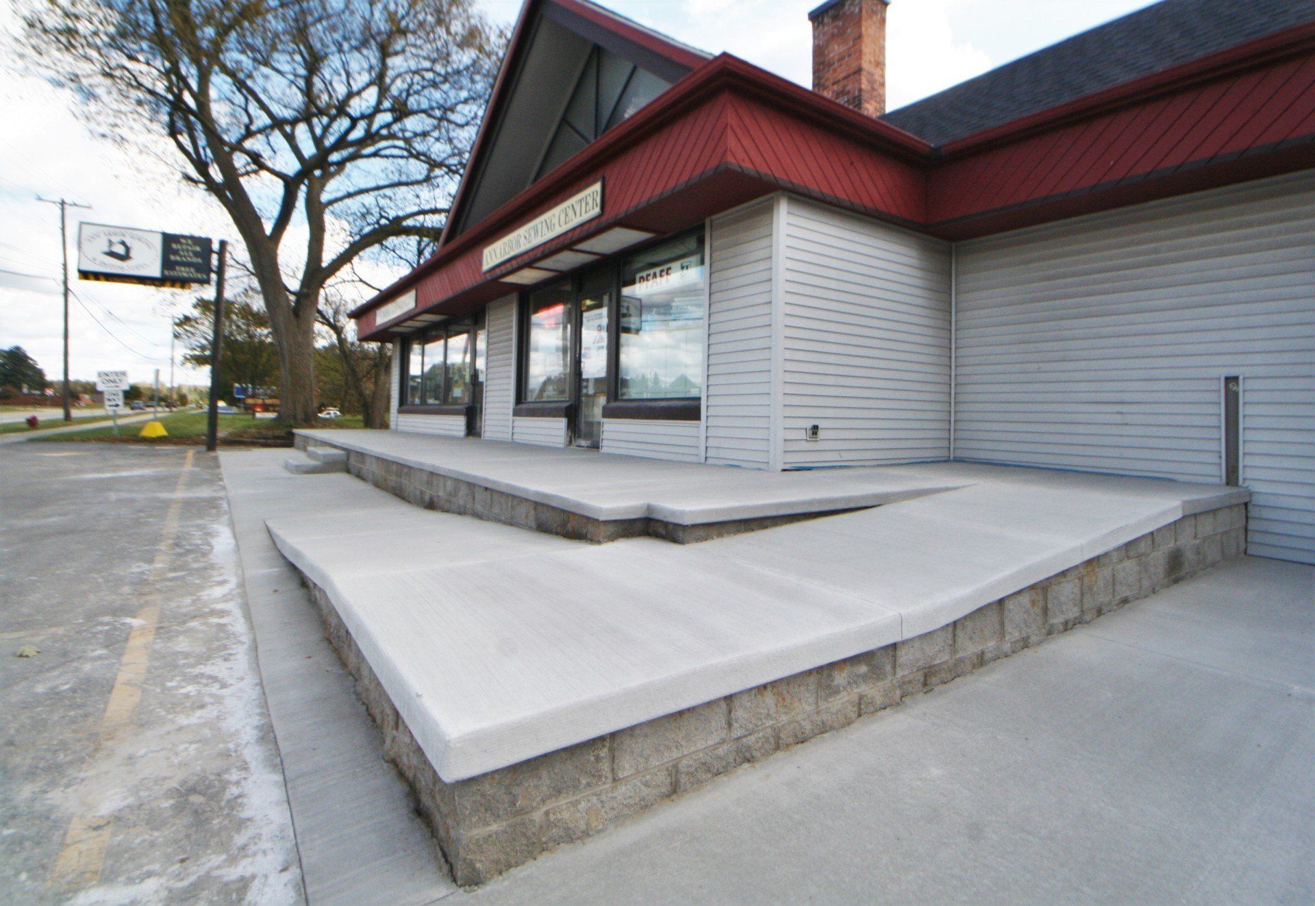 Exterior of a commercial building with a large concrete ramp and steps, under a red-trimmed roof