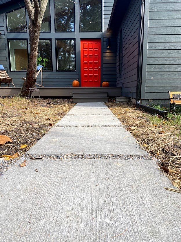 Front walkway leading to a house with a bright red front door and a pumpkin by the steps.
