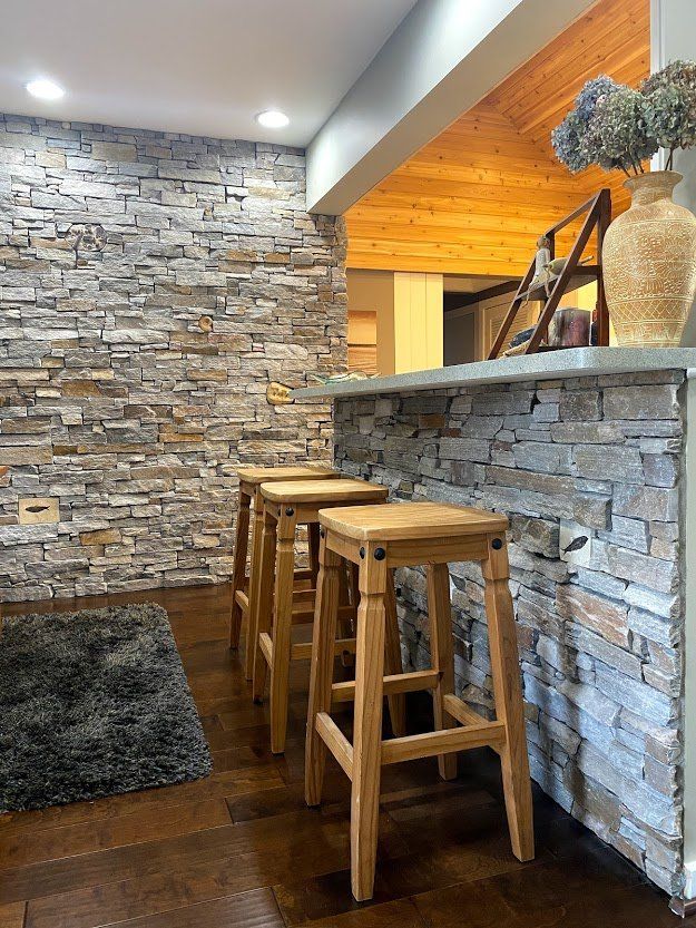 Stone bar interior with wooden stools, stacked-stone walls, and warm orange ceiling accents