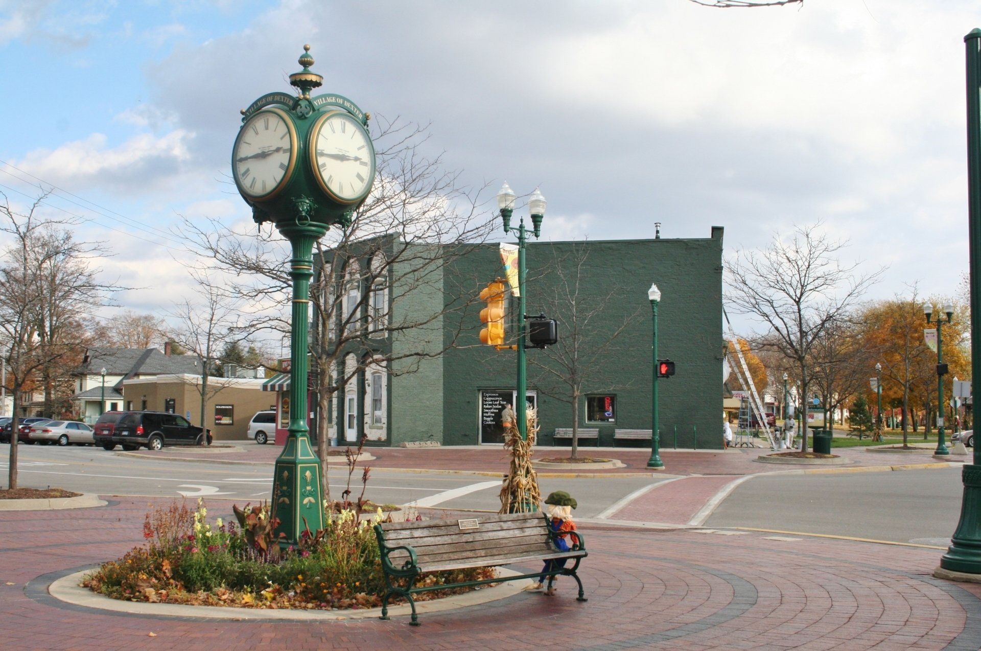 Small town intersection with a green clock and a brick building on a cloudy day