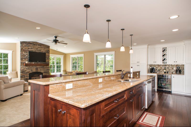 Bright modern kitchen with large island, granite counters, pendant lights, and fireplace in open living space