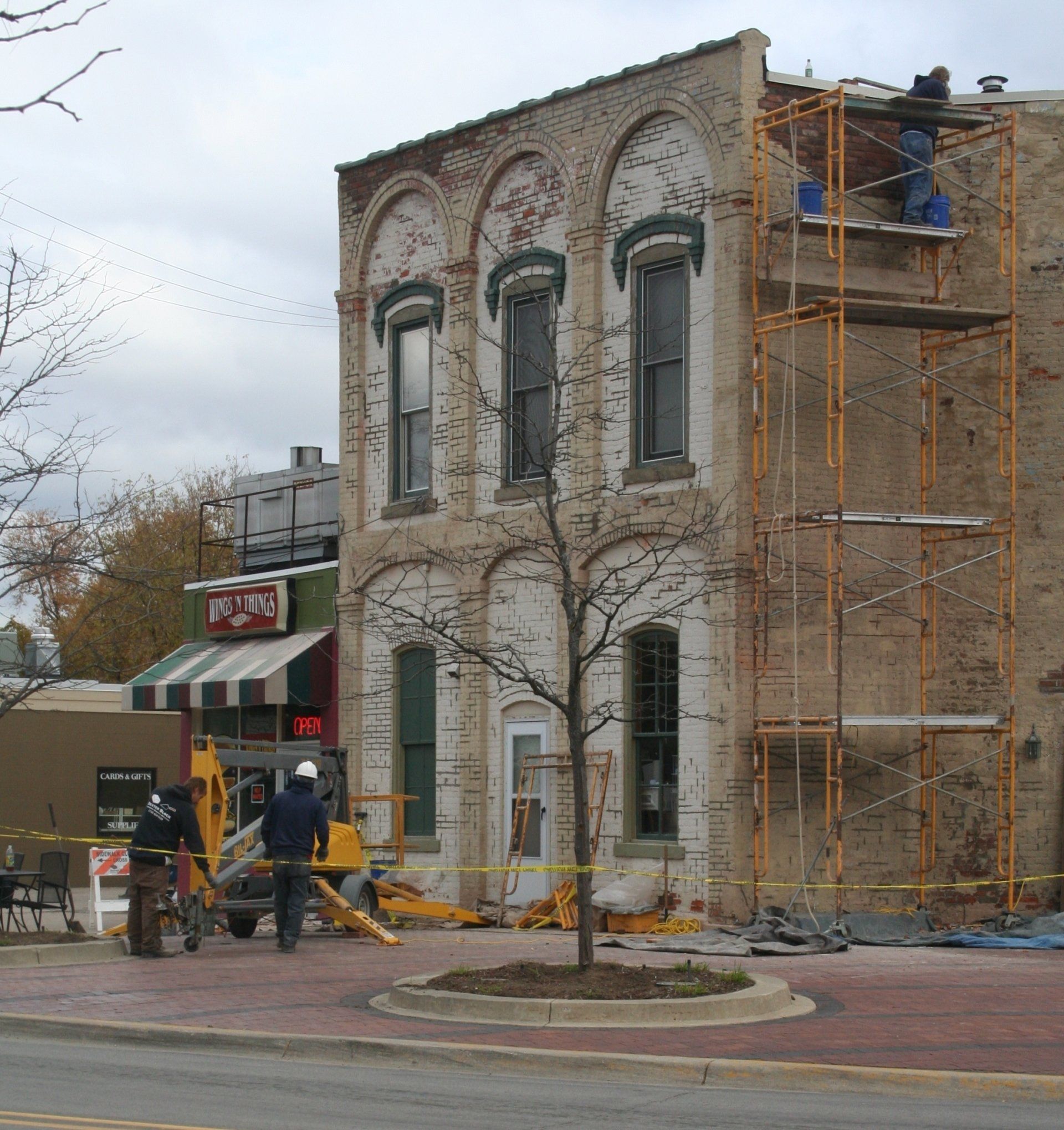 Historic stone building under renovation with scaffolding and construction equipment on a city street