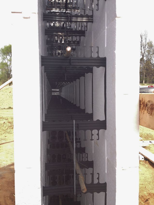 Dim stairwell with repeating white columns and black metal railings leading upward.
