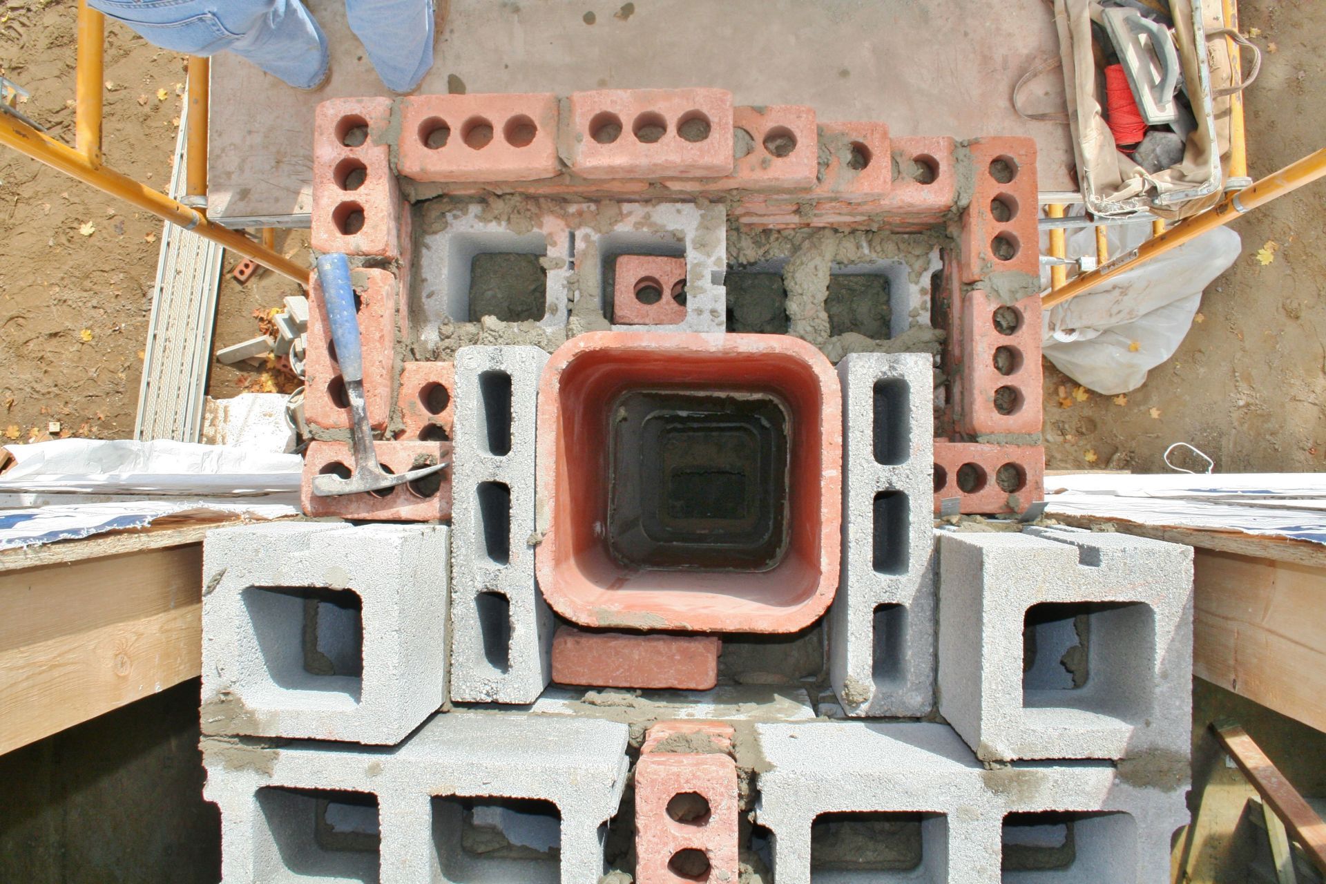 Top view of stacked construction bricks and blocks around a square central opening on a worksite