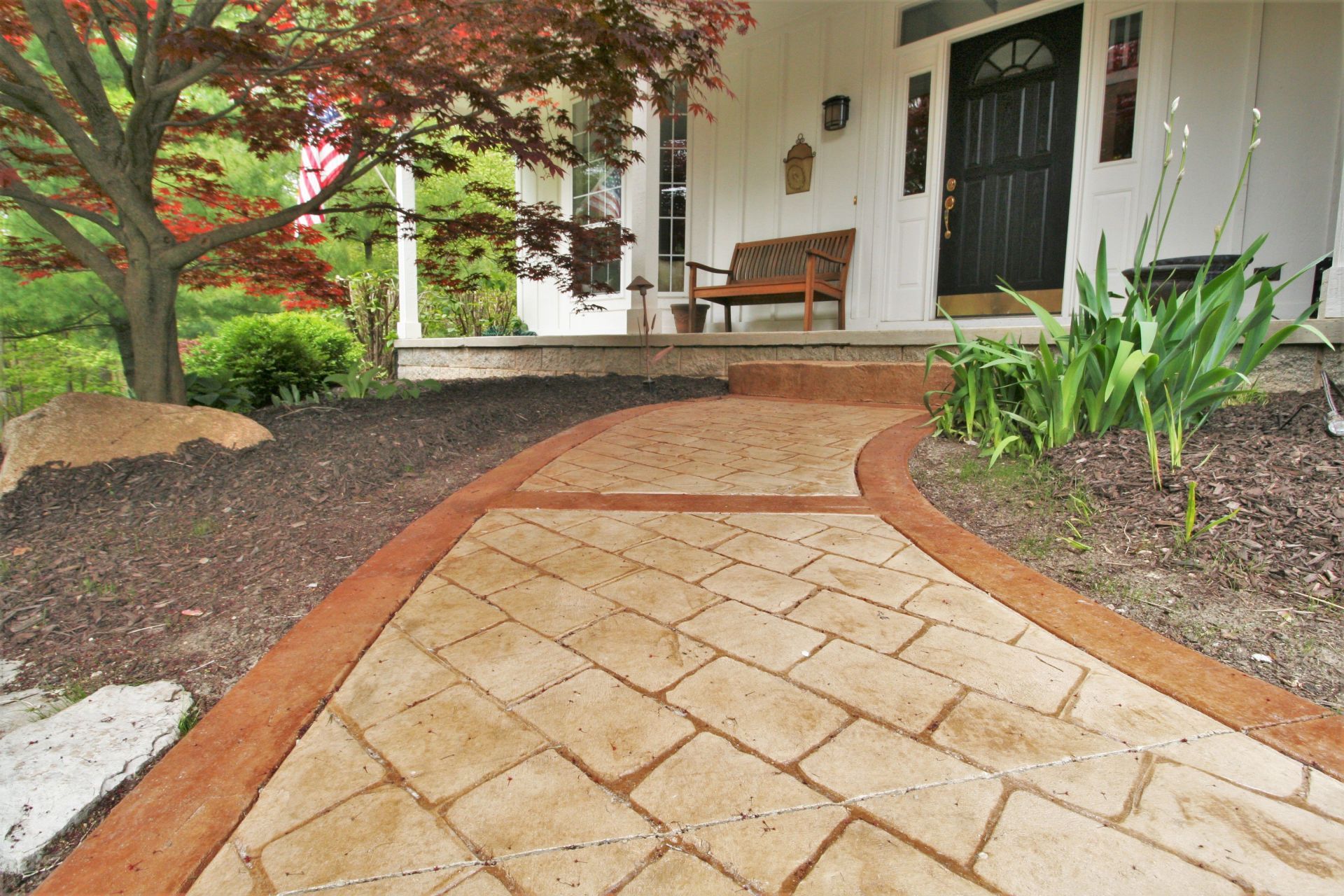 Curved stamped concrete walkway leading to a home's covered front porch
