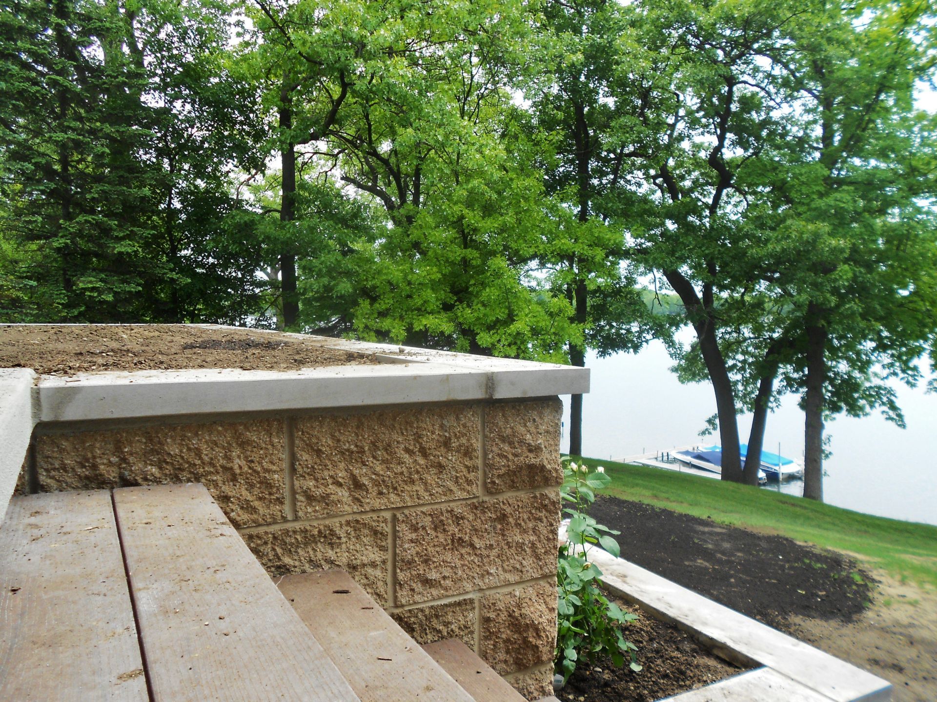 Stone bench by a lakeside path with trees and a glimpse of water in the background