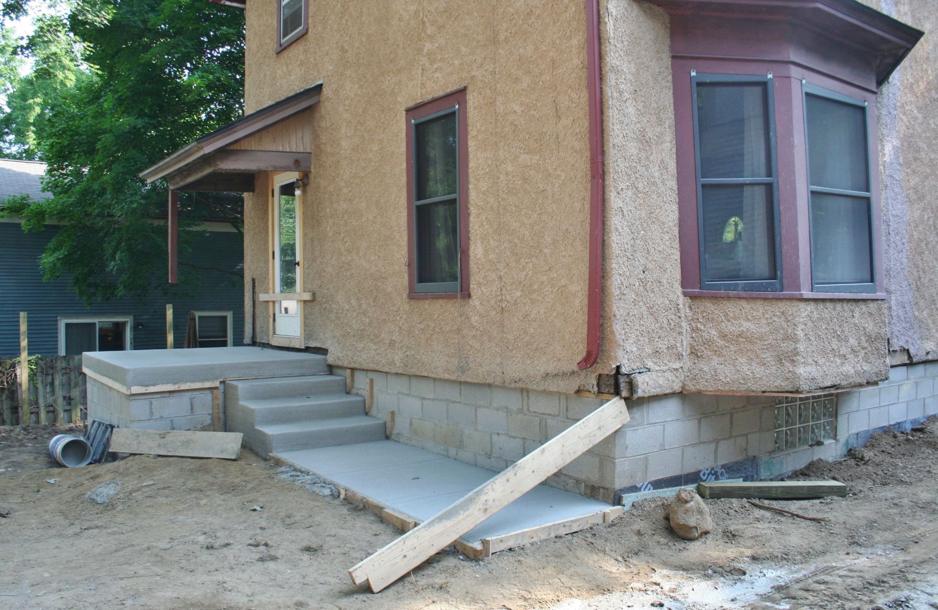 House entrance with concrete steps and a temporary wooden ramp under construction