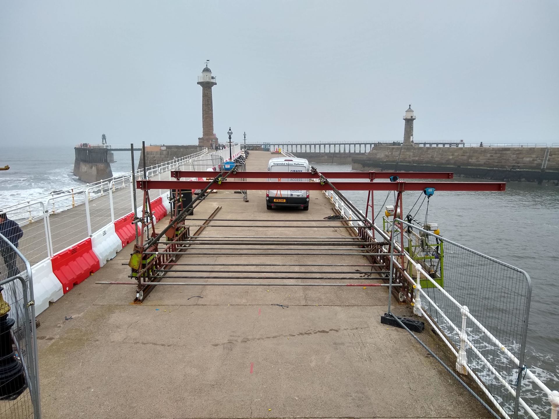 Rigging system extending a working platform over a sea wall in Whitby
