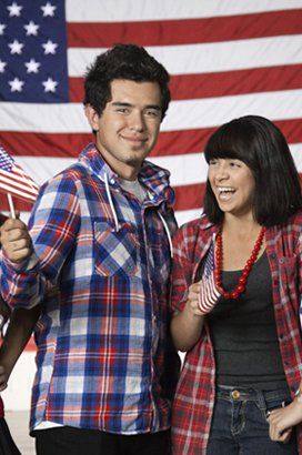 A man and a woman are holding american flags in front of an american flag.