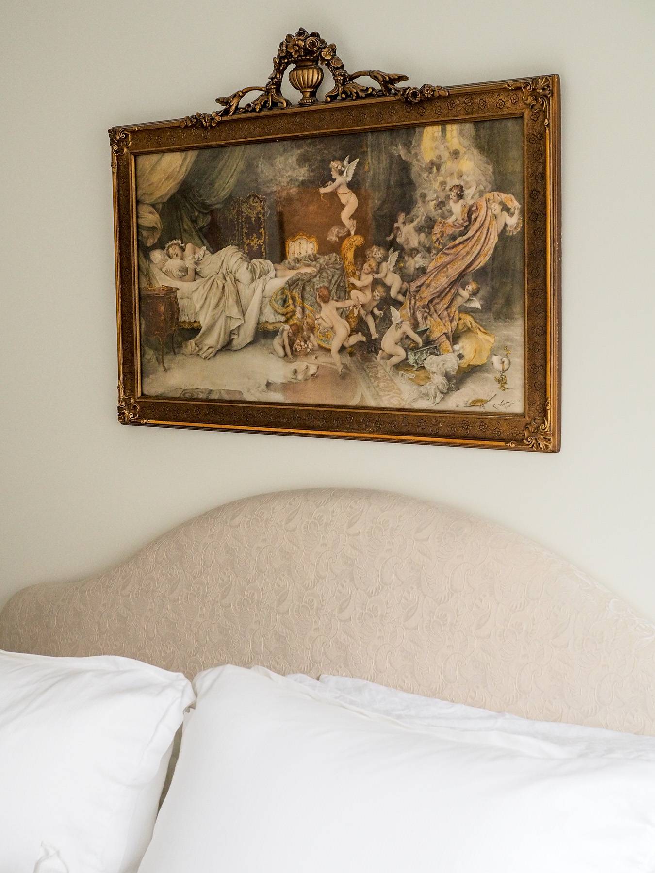 framed painting above a bedframe
