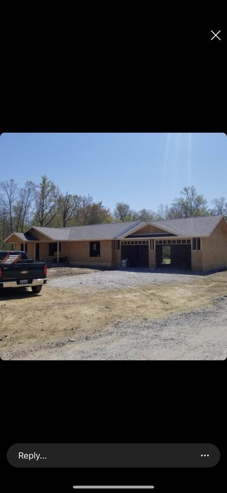 A new single-story house with a tan exterior, dark roof, and attached two-car garage under a clear blue sky.