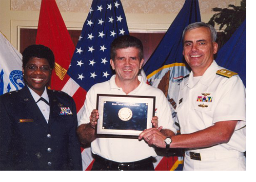 A man in a military uniform is holding a framed picture
