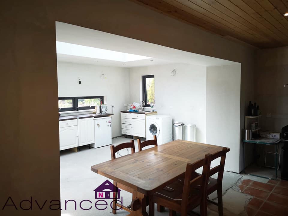 A kitchen with a wooden table and chairs and a washing machine