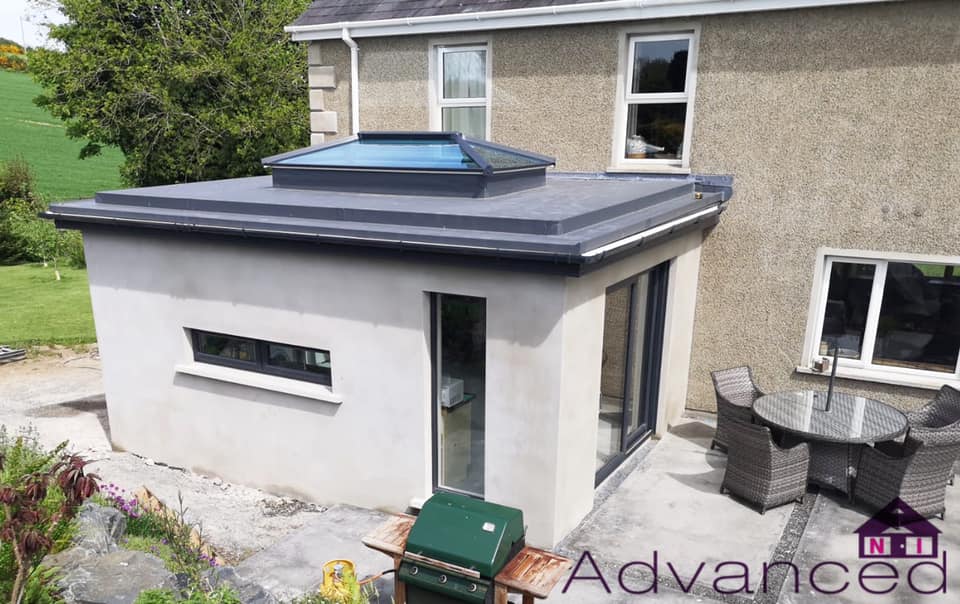 A house with a roof extension and a table and chairs on the patio.
