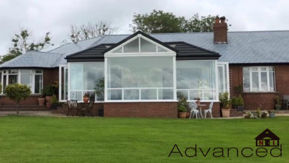 A house with a screened in porch and a large lawn in front of it.