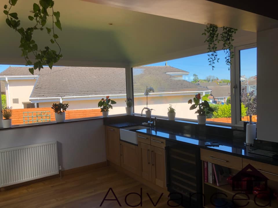 A kitchen with a lot of windows and plants on the counter