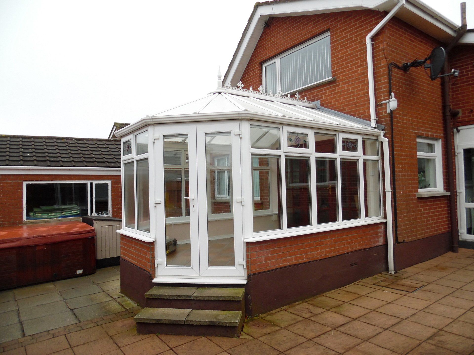 A brick house with a white conservatory on the side of it