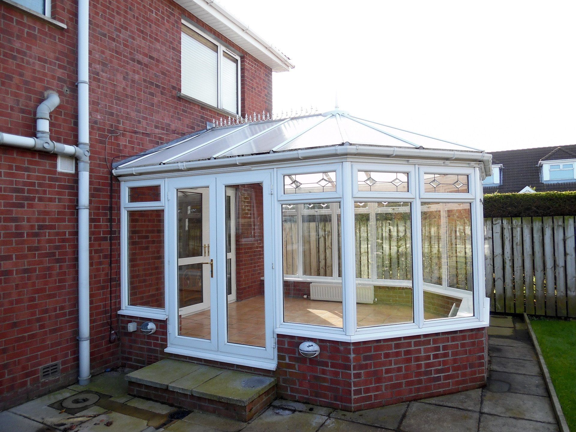 A red brick house with a white conservatory in the backyard.