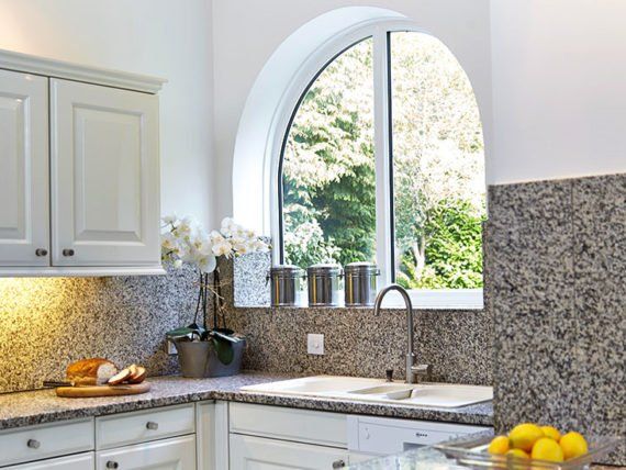 A kitchen with a large window and a bowl of lemons on the counter