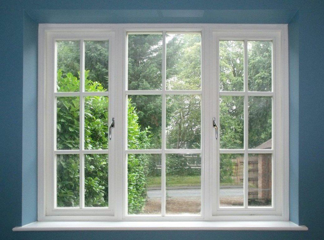 A white window with a view of trees in a room with blue walls.