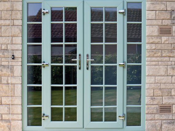 A pair of green french doors on a brick building