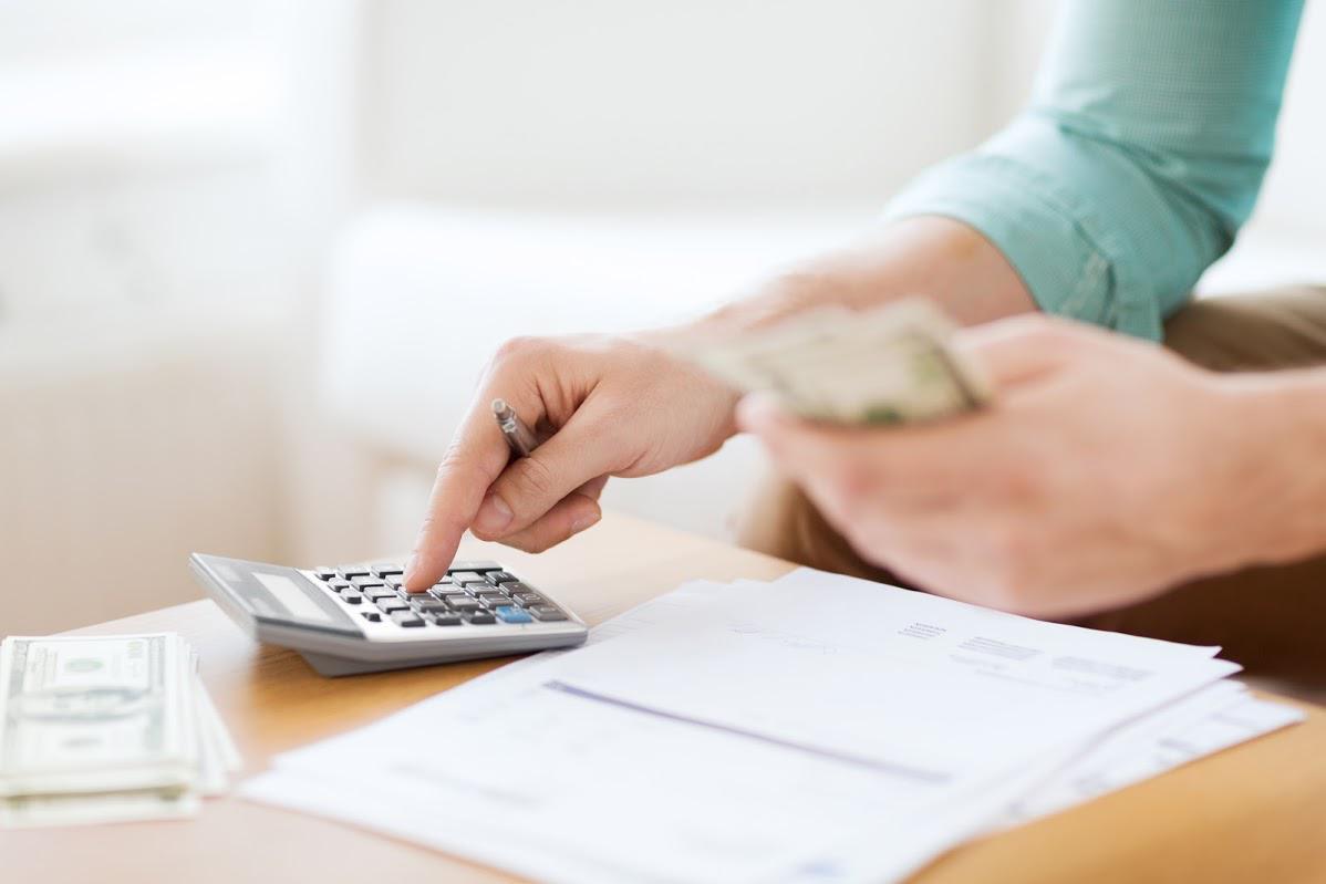 A Person Is Holding Money And Using A Calculator — Cape Coral, FL — Dramko Diane Attorney At Law