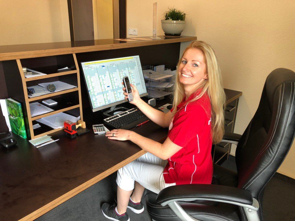 Eine Frau in einem roten Hemd sitzt an einem Schreibtisch mit einem Computer