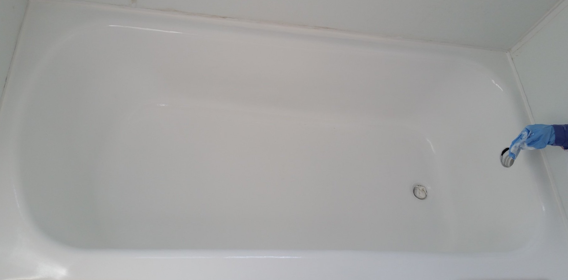A person is cleaning a bathtub with a brush.