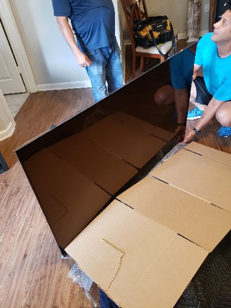 A man in a blue shirt is kneeling down next to a cardboard box