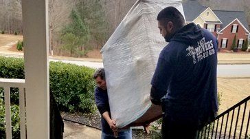 Two men are carrying a large piece of furniture up a set of stairs.