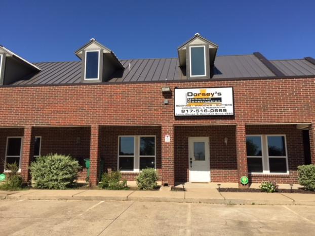 Dorsey's Hair Design salon exterior with brick facade, metal roof, and dormers under a blue sky.