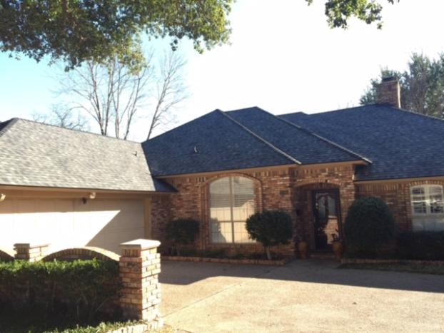 Brick house with dark roof and attached garage; sunny day.
