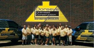 Group of people in yellow shirts posing in front of brick wall, Dorsey's Unlimited Construction 