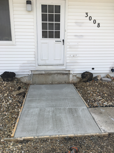 Front entrance with white door, concrete ramp, and house number 3008 on white siding