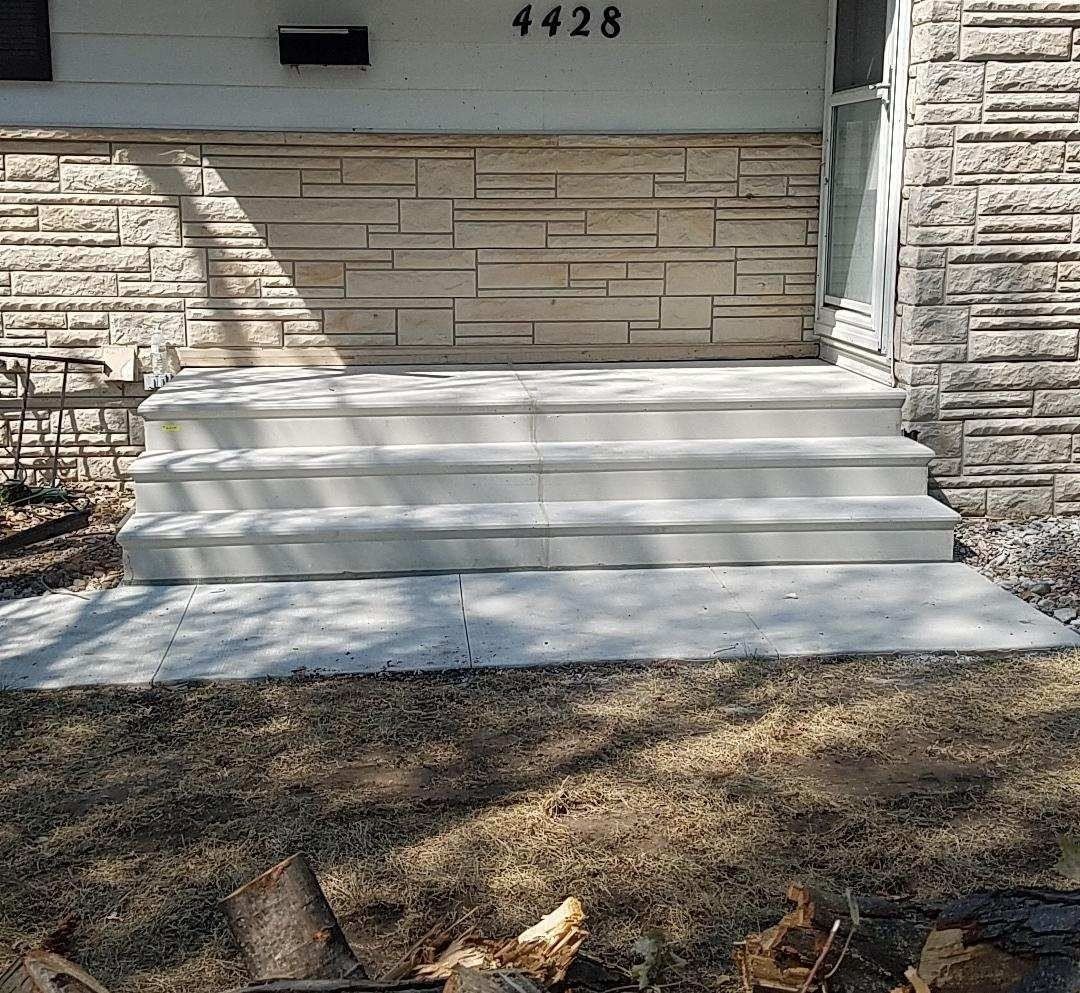 Concrete front steps leading to a stone house entrance with house number 4428 above the door