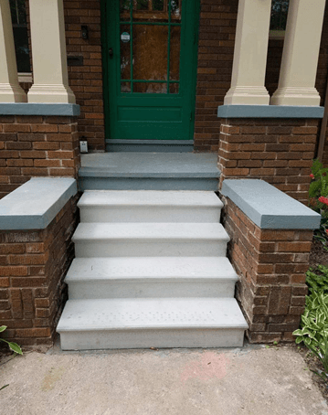Front porch with white steps, brick sides, and a green front door