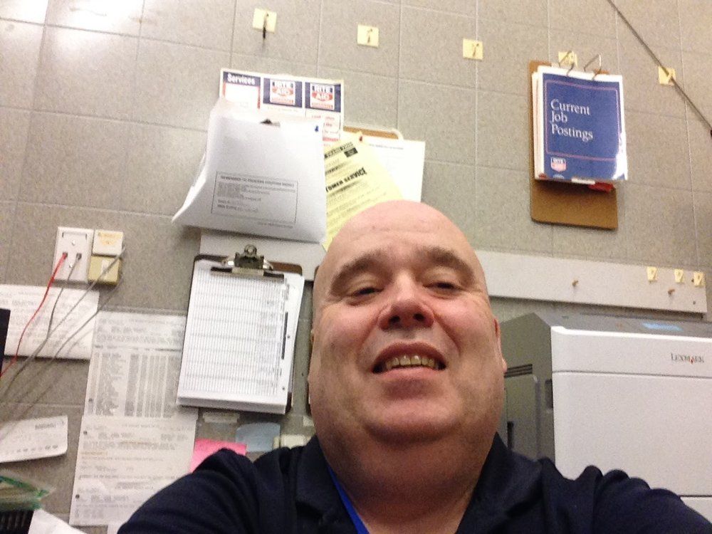 A man taking a selfie in front of a wall with papers on it