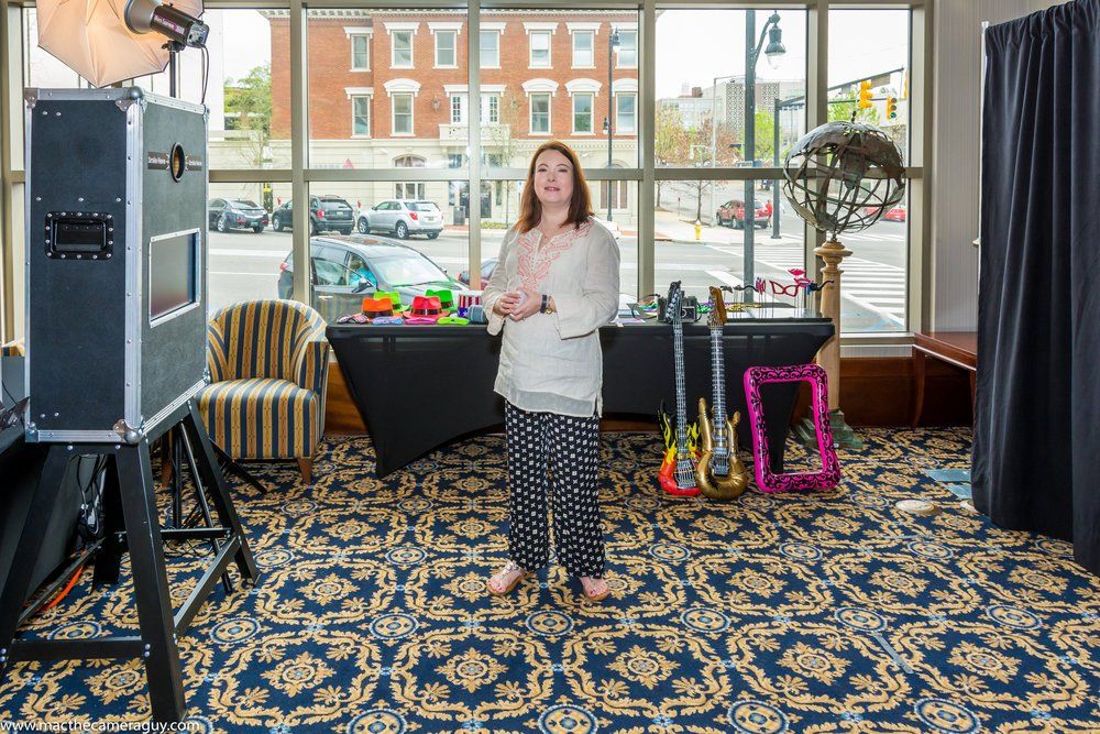 A woman is standing in front of a photo booth in a room.