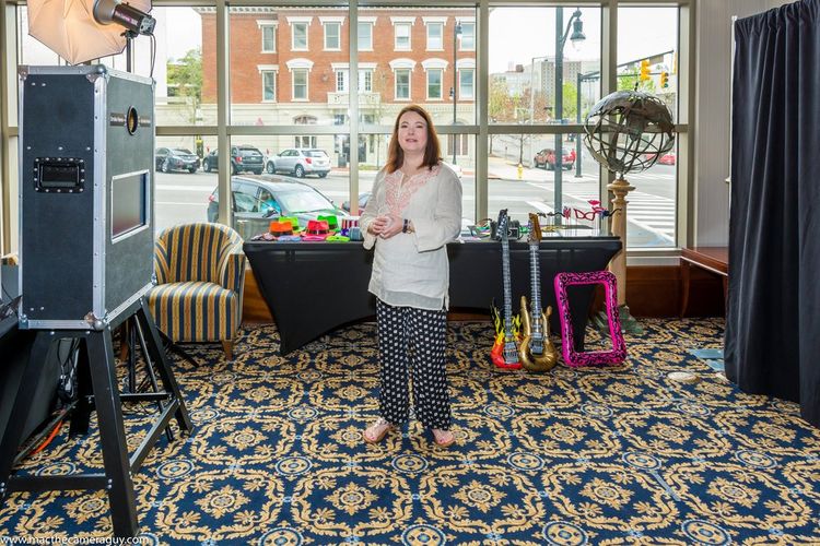 A woman is standing in front of a photo booth in a room.