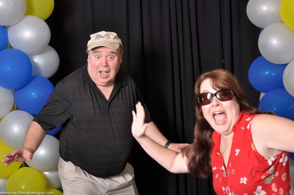A man and a woman are posing for a picture in front of balloons.