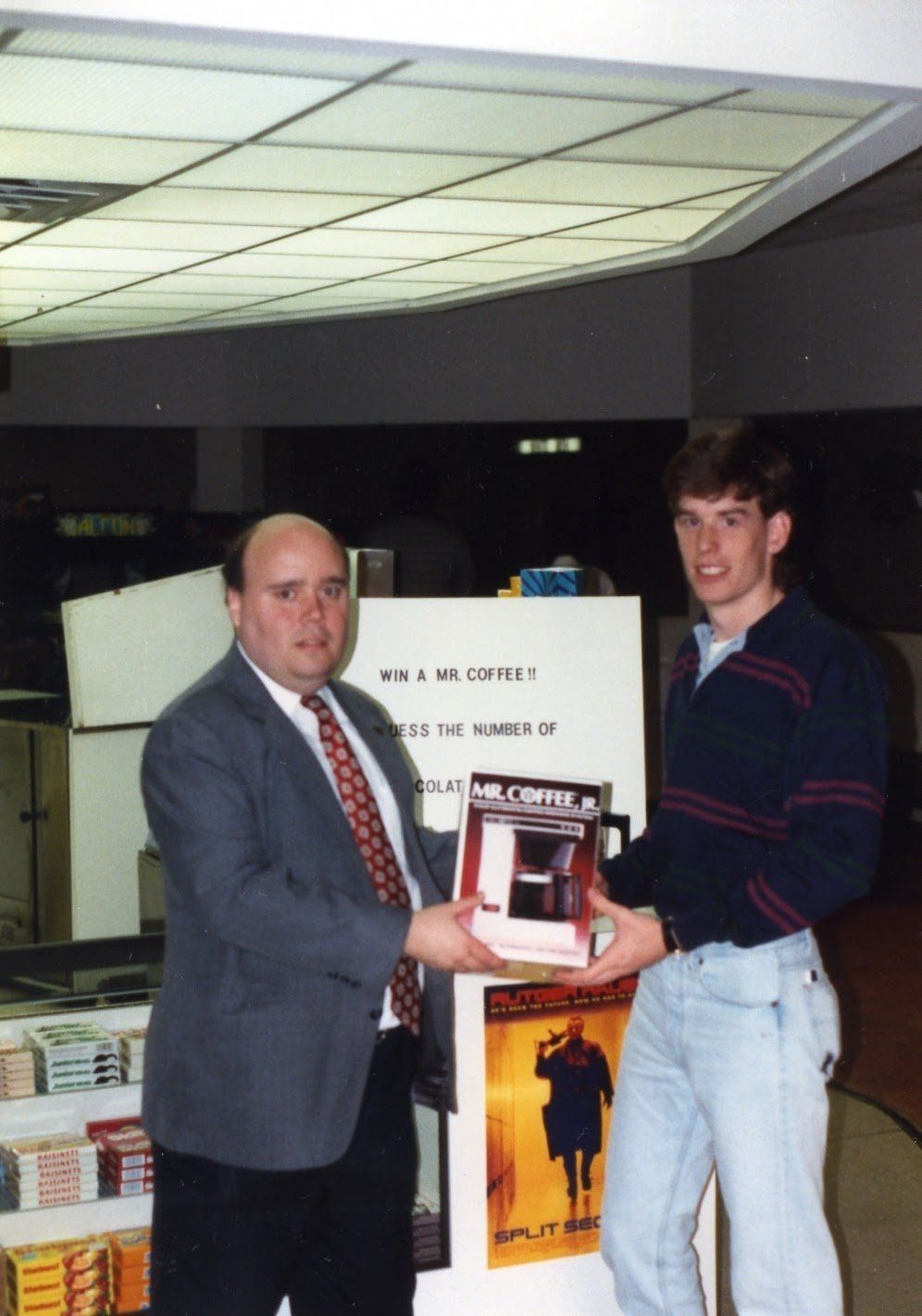 A man in a suit and tie is handing a book to another man