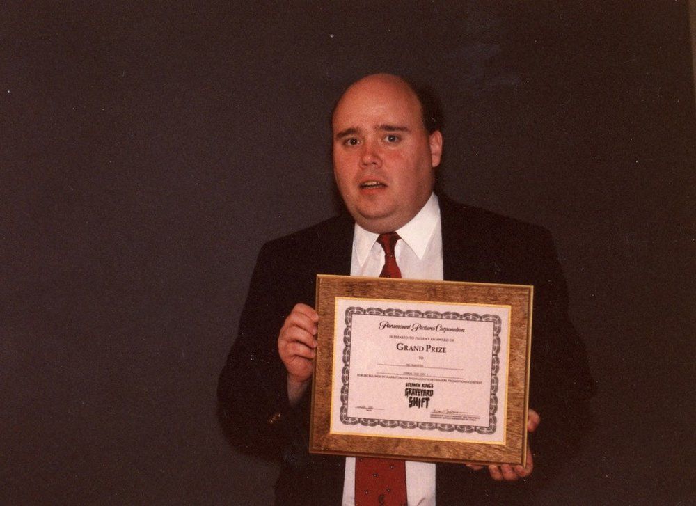 A man in a suit and tie is holding a framed certificate